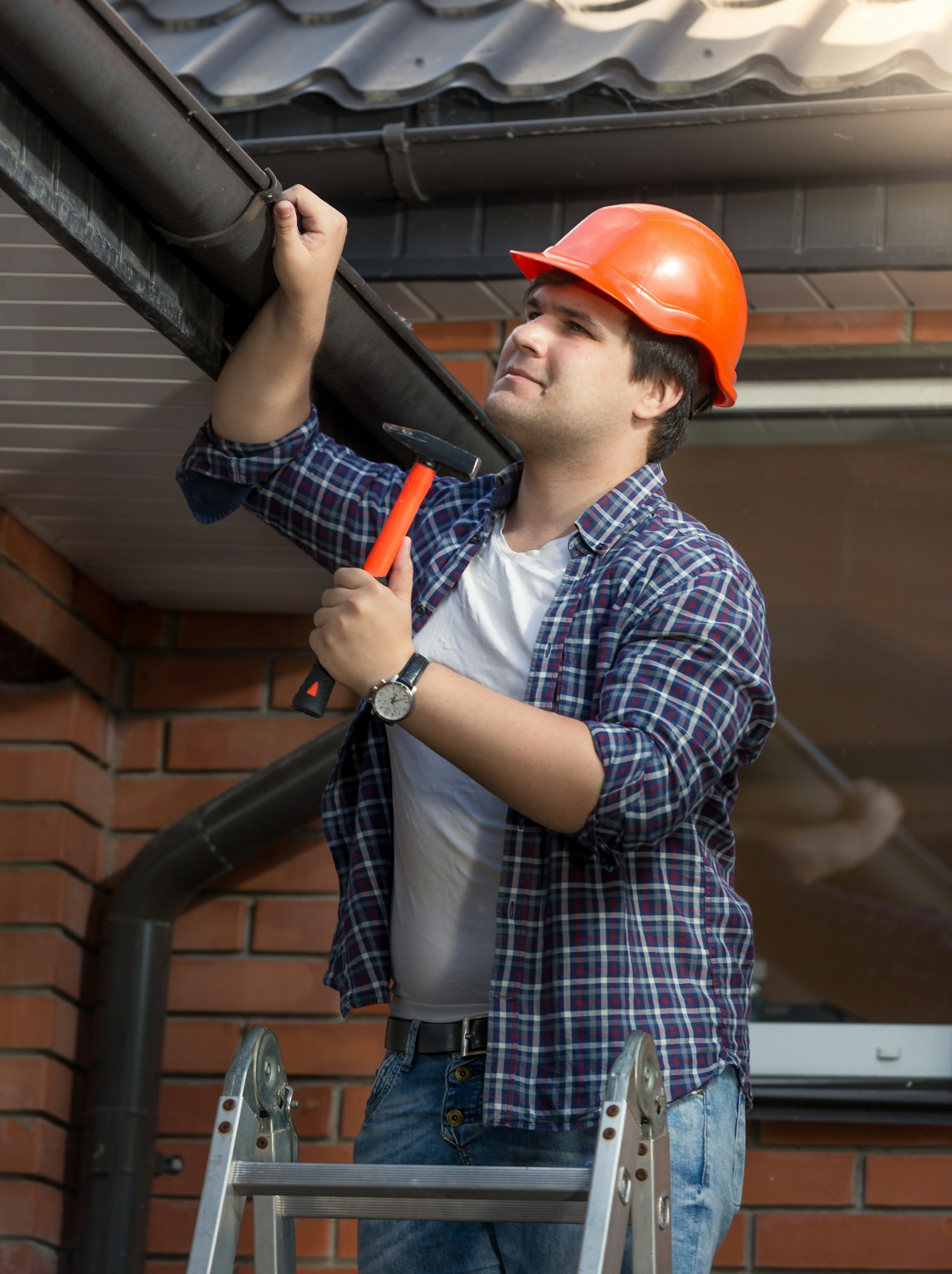Portrait of carpenter in hardhat examining house roof